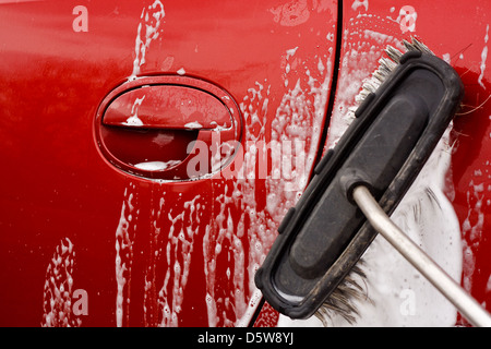 Laver la voiture avec une brosse savonneuse à un lavage de voiture à monnayeur Banque D'Images