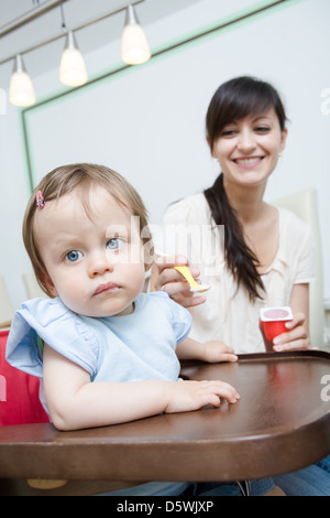 Little baby girl eating a yaourts Banque D'Images