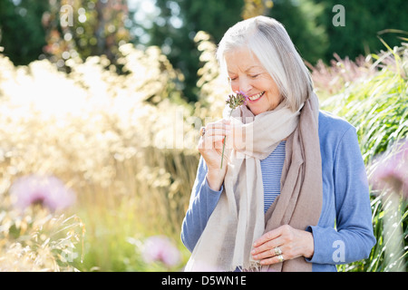 Plus woman smelling flowers outdoors Banque D'Images