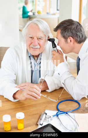 Doctor examining older man's ear au house call Banque D'Images