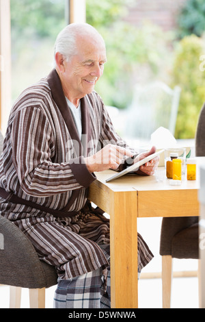 Older Man using tablet computer at table Banque D'Images