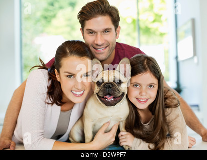Smiling family hugging dog Banque D'Images