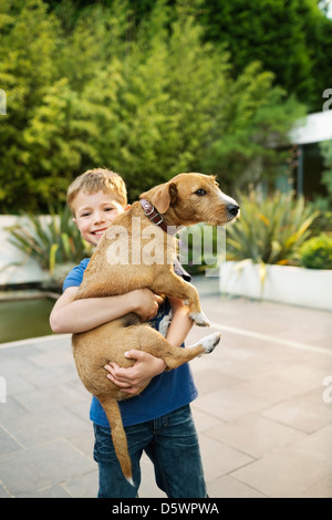 Smiling boy holding dog outdoors Banque D'Images