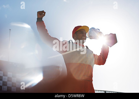 Cheering racer holding trophy sur la voie Banque D'Images