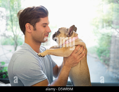 Smiling man holding dog indoors Banque D'Images