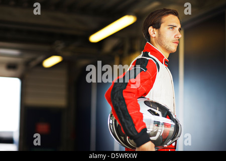 Racer holding helmet in garage Banque D'Images