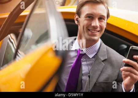 Businessman climbing out of taxi Banque D'Images