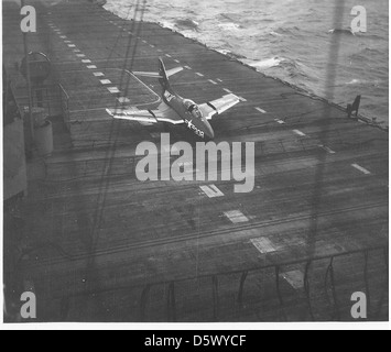 Le Grumman F9F-6 Cougar, converti aux normes QF-9G pour la pratique des cibles, effectue un atterrissage en collision avec une barrière sur le poste de pilotage d'un porte-avions inconnu. Le F9F-6 était un chasseur à réaction à porte-avions utilisé par la marine américaine dans les années 1950 Banque D'Images