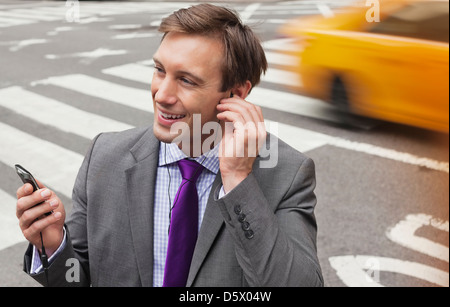 Businessman talking on cell phone on city street Banque D'Images