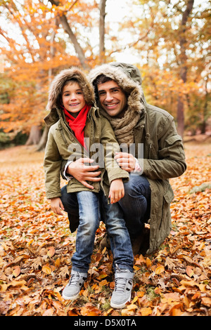 Père et fils debout dans les feuilles d'automne Banque D'Images