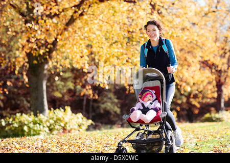 Femme en marche avec poussette de bébé dans le parc Banque D'Images