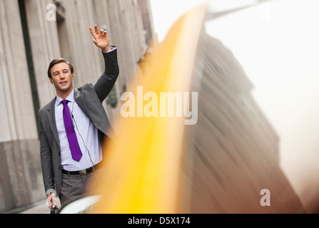 Businessman hailing taxi on city street Banque D'Images