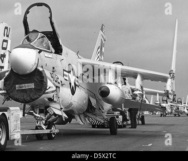 Les marins remorquent un LTV A-7E Corsair II du Attack Squadron 195 à l'USS Kitty Hawk (CV-63) pour le chargement. L'A-7E était un avion d'attaque capable de transporter des porte-avions, largement utilisé pour les missions d'attaque au sol pendant la guerre froide. Banque D'Images