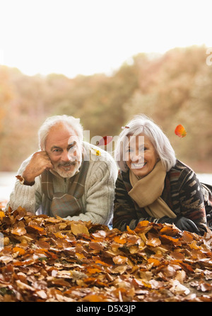 Vieux couple laying in autumn leaves Banque D'Images