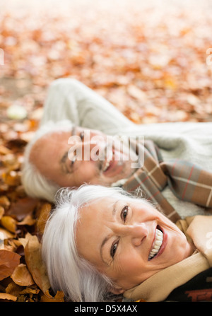 Vieux couple laying in autumn leaves Banque D'Images