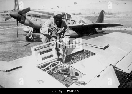 'Un des aviateurs tuskeegee africains-américains membres de l'armée us Chargement de munitions pour une mitrailleuse de calibre .50 dans l'aile d'un North American P-51 'mustang', Italie, sept. 1944. Banque D'Images