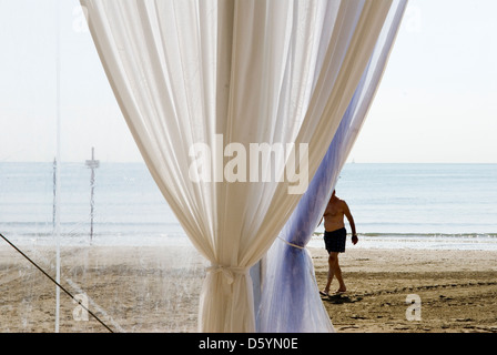 Venise Italie Venise Lido Venise Mer Adriatique la plage publique. Un homme italien solitaire vacances à pied le long de la plage. Tente d'auvent de plage. HOMER SYKES des années 2000 Banque D'Images