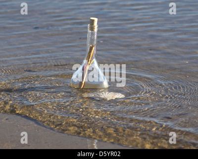 Message scellé dans la bouteille sur la plage de sable Banque D'Images