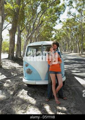 Young couple leaning contre l'avant du camping-van stationné par la route Banque D'Images