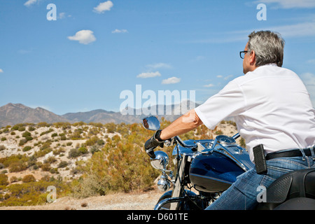 Senior man riding moto à travers le désert Banque D'Images