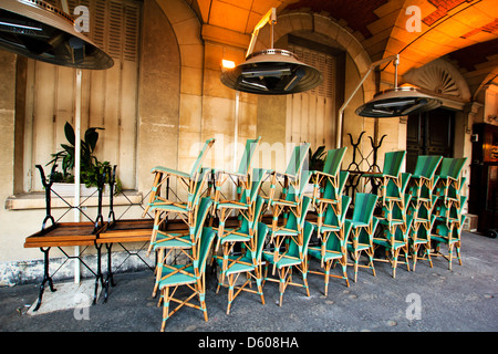 Chaises en osier disposés en piles avant la fermeture du café, Marais, Place des Vosges, Paris, France Banque D'Images