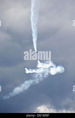 Vue verticale de quatre avions en formation avec des traînées de vapeur production de motifs lors d'une acrobatie afficher les performances de l'équipe. Banque D'Images