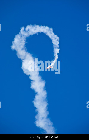 Vue verticale d'un monoplan contre un ciel bleu avec blanc vapeur faisant une boucle la boucle lors d'une acrobatie. Banque D'Images