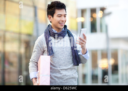 Jeune homme à la mode avec contrôle de cadeaux smart phone Banque D'Images