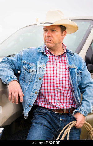 Texas Cowboy - Middle-aged man de 46 ans avec chapeau de cowboy et corde appuyée contre camionnette Banque D'Images