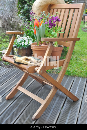 Les fleurs de printemps dans des pots placés sur une chaise sur une terrasse en bois Banque D'Images