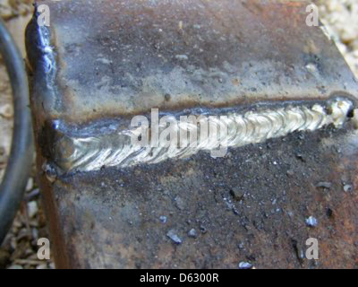 Gros plan d'un procédé de soudage manuel à l'arc métallique (MMAW), montrant l'arc UV et la lumière bleue émis pendant le soudage. L'image met en évidence la lumière intense produite et le bouclier de protection nécessaire pour la sécurité. Banque D'Images