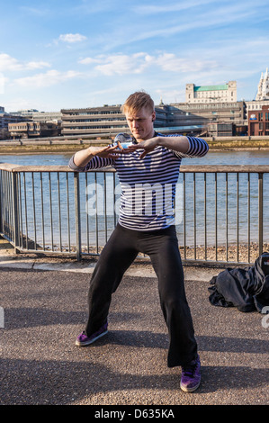 Un artiste de rue qui jongle avec une boule de cristal sur la promenade de la Tamise, South Bank, Londres, Angleterre, Royaume-Uni. Banque D'Images