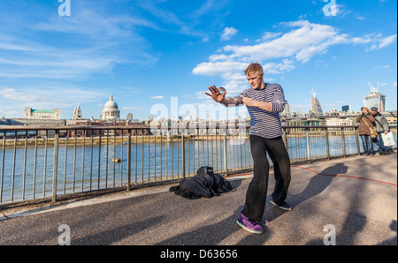 Un artiste de rue qui jongle avec une boule de cristal sur la promenade de la Tamise, South Bank, Londres, Angleterre, Royaume-Uni. Banque D'Images