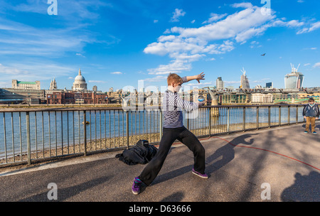 Un artiste de rue qui jongle avec une boule de cristal sur la promenade de la Tamise, South Bank, Londres, Angleterre, Royaume-Uni. Banque D'Images