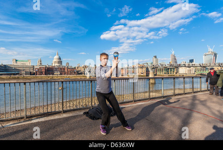 Un artiste de rue qui jongle avec une boule de cristal sur la promenade de la Tamise, South Bank, Londres, Angleterre, Royaume-Uni. Banque D'Images