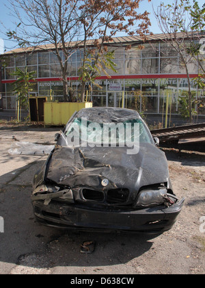 Scène d'une voiture impliquée dans un accident de la route, le véhicule étant gravement écrasé et endommagé. L'image capture les conséquences de l'accident sur la route. Banque D'Images