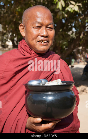 Le moine bouddhiste tenant un bol d'aumône contenant des dons, Bagan, Myanmar (Birmanie), Banque D'Images