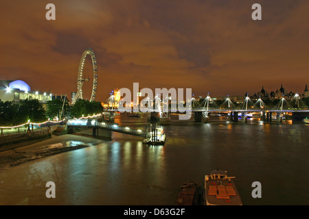 Le London Eye éclairés la nuit, près de la Tamise avec le Hungerford Bridge. Banque D'Images