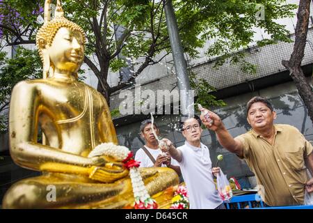 Bangkok, Thaïlande. 12 avril 2013. Les thaïs saupoudrer les huiles parfumées sur le Phra Buddha Sihing alors que c'est ont défilé dans les rues de Bangkok sur la première journée d'Songrkran. Le Phra Buddha Sihing vénéré, une statue de Bouddha, s'effectue par camion à travers les rues de Bangkok afin que les gens peuvent faire des offrandes et se baigner dans les huiles parfumées. Songkran est célébré en Thaïlande comme le traditionnel jour de l'an, du 13 au 16 avril.Credit : ZUMA Press, Inc. / Alamy Live News Banque D'Images