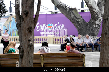 Männer und Frauen sitzen am Donnerstag (24.05.2012) auf einem Platz à Bakou (Aserbaidschan) vor einem Plakat, das auf den derzeit dort stattfindenden Eurovision Song Contest hinweist. ESC-Im Finale treten am Samstag (26.05.2012) 26 un Länder. Photo : Joerg Carstensen  + + +(c) afp - Bildfunk + + + Banque D'Images