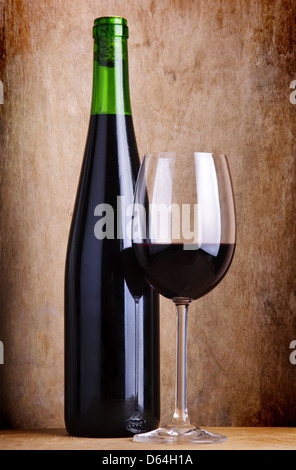 Composition de la vie toujours avec le verre et bouteille de vin rouge sur un sol en bois vintage grunge background Banque D'Images