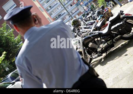 Un agent de police se place en avant des motos des membres du club Satudarah à bascule néerlandais donnent une conférence de presse au pavillon du club Clown-Town à Duisburg, Allemagne, 02 juin 2012. Autour de 300 clubs différents de rockers se sont réunis pour fonder un chapitre de la Dutch Satudarah. Photo : DANIEL NAUPOLD Banque D'Images