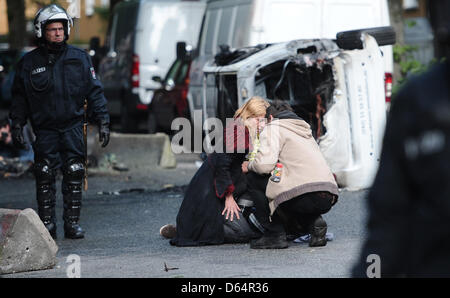 Les agents de police clairement le domaine de barricades, tandis que deux femmes prennent soin d'un homme blessé, qui a protesté contre un rassemblement néo-nazi avec la devise 'Journée de l'avenir" allemand à Hambourg, Allemagne, 02 juin 2012. Plusieurs milliers de personnes ont manifesté contre la marche de l'extrême droite. Photo : Christian Charisius Banque D'Images