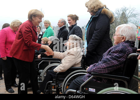 Melle-Wellingholzhausen, Allemagne. 12 avril 2013. La chancelière allemande Angela Merkel (L) accueille les personnes âgées assis dans un fauteuil roulant à l'échelon supérieur de la rue Centre Konrad Melle-Wellingholzhausen, Allemagne, 12 avril 2013. Merkel a recueilli des informations sur le concept de centres de retraite, dans laquelle les personnes âgées peuvent vivre ensemble dans des communautés. Photo : Ingo Wagner/dpa/Alamy Live News Banque D'Images