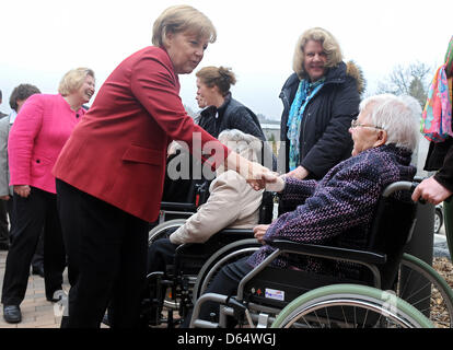 Melle-Wellingholzhausen, Allemagne. 12 avril 2013. La chancelière allemande Angela Merkel (L) accueille les personnes âgées assis dans un fauteuil roulant à l'échelon supérieur de la rue Centre Konrad Melle-Wellingholzhausen, Allemagne, 12 avril 2013. Merkel a recueilli des informations sur le concept de centres de retraite, dans laquelle les personnes âgées peuvent vivre ensemble dans des communautés. Photo : Ingo Wagner/dpa/Alamy Live News Banque D'Images