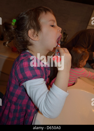 Petite fille se brosser les dents à l'évier Banque D'Images