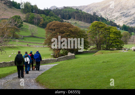 Un groupe d'hommes marcher dans le district du lac avec leurs chiens sur les pistes. Banque D'Images