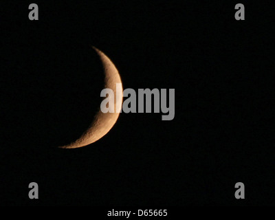 Un croissant de lune ciré dans le ciel nocturne sombre, capturant la phase de la lune avec une forme de croissant éclairé par la lumière du soleil, au milieu de l'obscurité profonde de la nuit. Banque D'Images