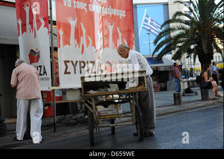 Un commerçant de la rue se tient devant une affiche électorale SYRIZA a la place Omonia à Athènes, Grèce, le 14 juin 2012. Les élections en Grèce aura lieu le 17 juin 2012. Photo : Emily Wabitsch Banque D'Images