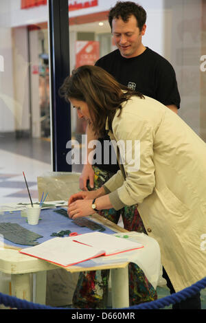 Southampton, UK. 12 avril 2013 - une dame bloquée vers le bas de la mosaïque avant d'être transférées à une sculpture de rhino pour rendez-vous ! Rhinos à Marlands Shopping Centre. Fini les Rhinos s'affiche sur les sentiers de la sculpture dans la ville cet été, de juillet à septembre avant de passer au Zoo de Marwell en octobre où ils seront vendus aux enchères. Produits bénéficieront de la faune Marwell, Wessex Heartbeat's High 5 Appel et la Rose Road Association. Crédit : Rob Arnold/Alamy Live News Banque D'Images